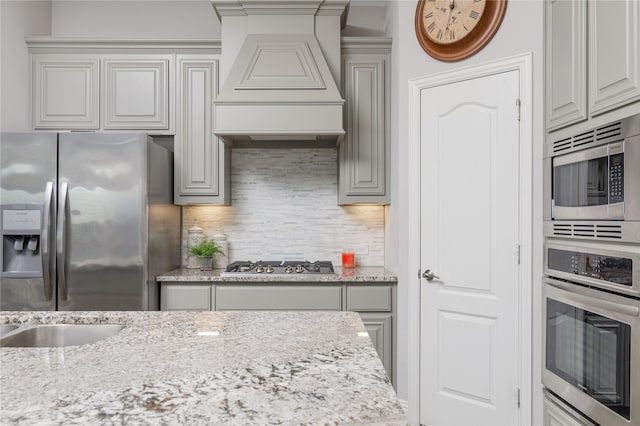 324 Roscoe Dr, Fate, TX 75087 - kitchen with appliances with stainless steel finishes, custom range hood, light stone counters, and tasteful backsplash