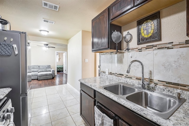 3624 Hardeman St, Fort Worth, TX 76119 - kitchen with tasteful backsplash, range, dark brown cabinetry, freestanding refrigerator, and ceiling fan