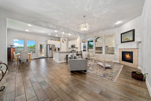 705 Rio Concho Trl, Mckinney, TX 75071 - living area featuring wood finish floors, recessed lighting, a tiled fireplace, and a chandelier