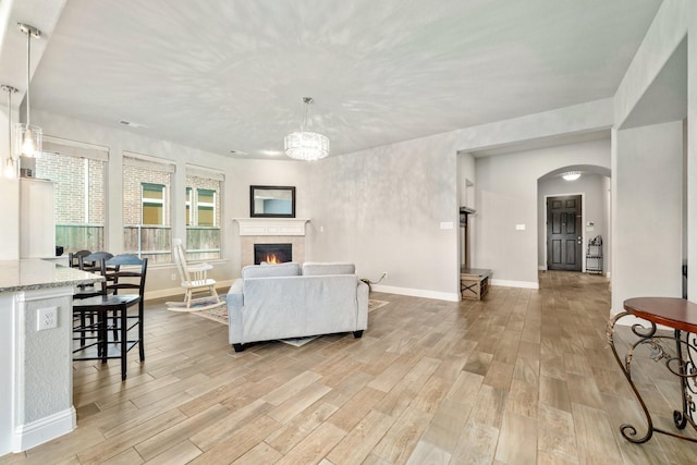 705 Rio Concho Trl, Mckinney, TX 75071 - living area with light wood-style flooring, arched walkways, a fireplace, and a chandelier