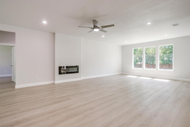 507 S 4th St, Grandview, TX 76050 - unfurnished living room with ceiling fan, light wood-style flooring, heating unit, a glass covered fireplace, and recessed lighting