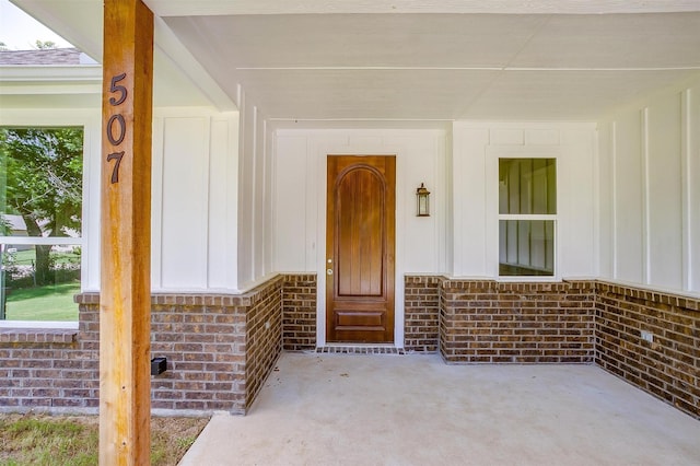 507 S 4th St, Grandview, TX 76050 - doorway to property with board and batten siding, brick siding, and covered porch