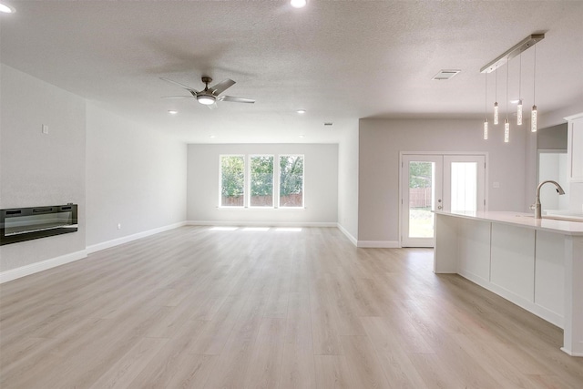 507 S 4th St, Grandview, TX 76050 - unfurnished living room featuring ceiling fan, light wood-style flooring, recessed lighting, a textured ceiling, and french doors