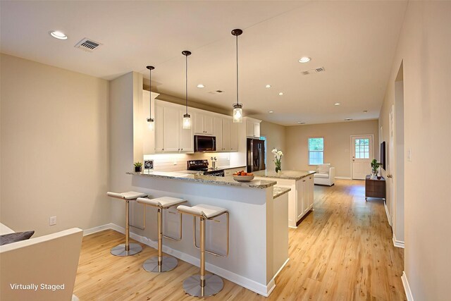 109 W Damon St, Terrell, TX 75160 - kitchen with stainless steel fridge, range with electric stovetop, black microwave, light wood-style flooring, and a peninsula