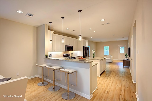 109 W Damon St, Terrell, TX 75160 - kitchen with stainless steel fridge, range with electric stovetop, black microwave, light wood-style flooring, and a peninsula