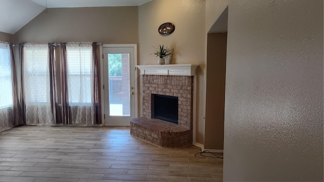 11521 Blanchard Dr, Frisco, TX 75035 - unfurnished living room featuring wood finished floors, a textured wall, vaulted ceiling, and a fireplace