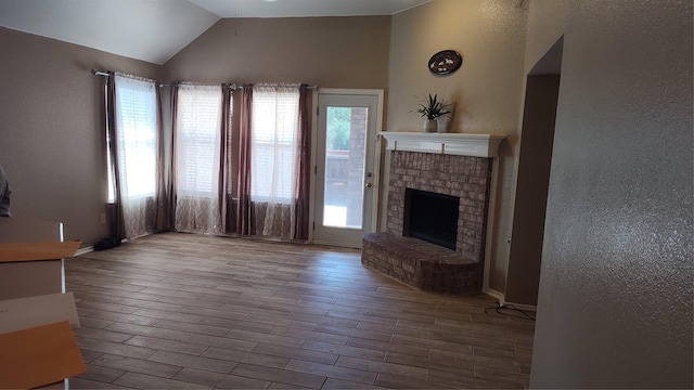 11521 Blanchard Dr, Frisco, TX 75035 - unfurnished living room with wood finished floors, lofted ceiling, a textured wall, and a fireplace