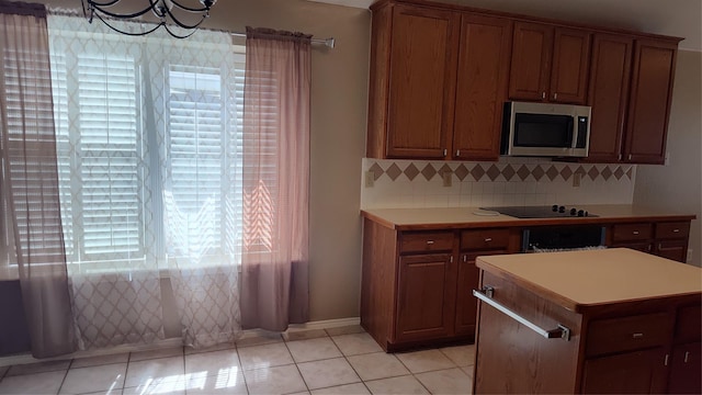 11521 Blanchard Dr, Frisco, TX 75035 - kitchen featuring stainless steel microwave, decorative backsplash, brown cabinetry, and light countertops