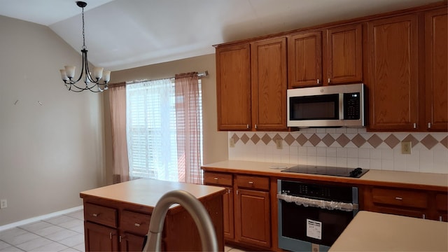 11521 Blanchard Dr, Frisco, TX 75035 - kitchen with black appliances, tasteful backsplash, lofted ceiling, brown cabinets, and hanging light fixtures