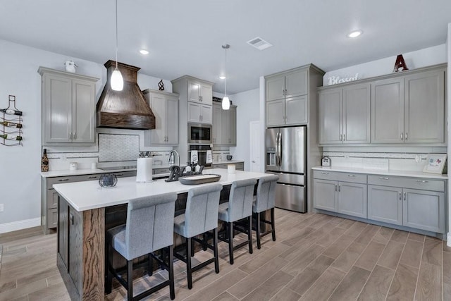 3036 Deer Ct, Weatherford, TX 76085 - kitchen featuring stainless steel appliances, gray cabinets, tasteful backsplash, custom exhaust hood, and a breakfast bar area