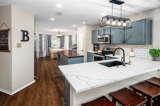 1722 Chestnut St, Anna, TX 75409 - kitchen with appliances with stainless steel finishes, a chandelier, a kitchen island, dark wood finished floors, and a peninsula