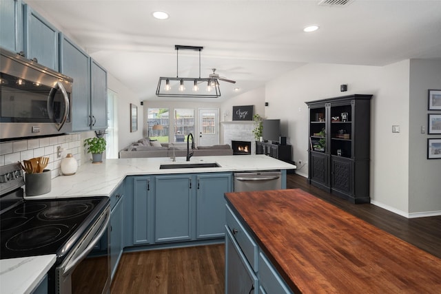 1722 Chestnut St, Anna, TX 75409 - kitchen featuring stainless steel appliances, butcher block countertops, a warm lit fireplace, open floor plan, and blue cabinets