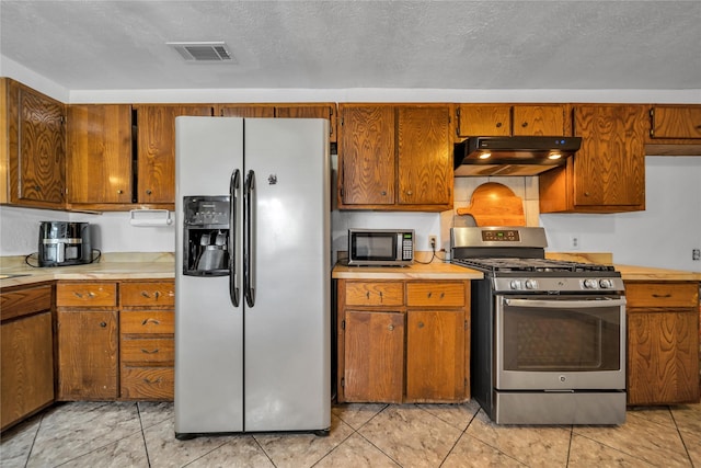 6354 Cinnamon Oaks, Dallas, TX 75241 - kitchen with appliances with stainless steel finishes, under cabinet range hood, light countertops, and brown cabinetry
