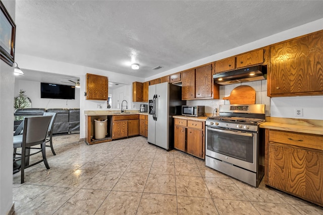 6354 Cinnamon Oaks, Dallas, TX 75241 - kitchen featuring stainless steel appliances, under cabinet range hood, light countertops, brown cabinets, and a textured ceiling