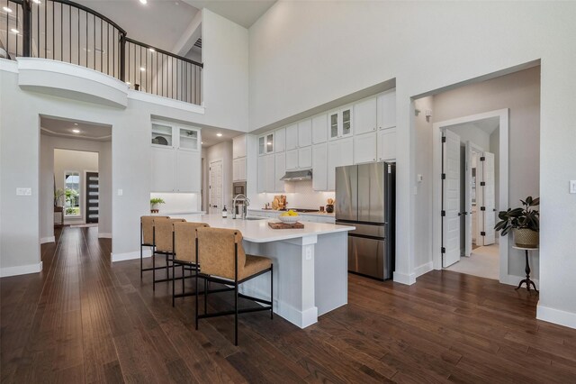 233 Kirkpatrick Ct, Argyle, TX 76226 - kitchen featuring stainless steel appliances, under cabinet range hood, light countertops, a large island with sink, and dark wood-type flooring