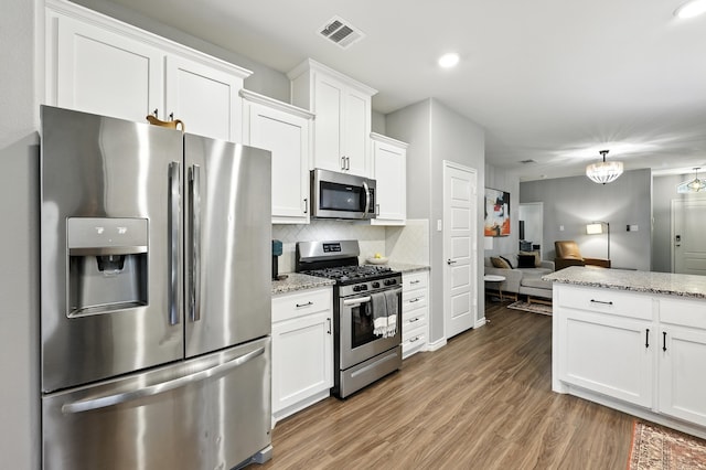 2136 Miramar Dr, Little Elm, TX 75068 - kitchen with stainless steel appliances, light wood-style floors, decorative backsplash, white cabinetry, and recessed lighting