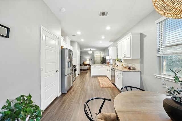 2136 Miramar Dr, Little Elm, TX 75068 - kitchen with white cabinets, stainless steel appliances, light wood-type flooring, light stone counters, and recessed lighting
