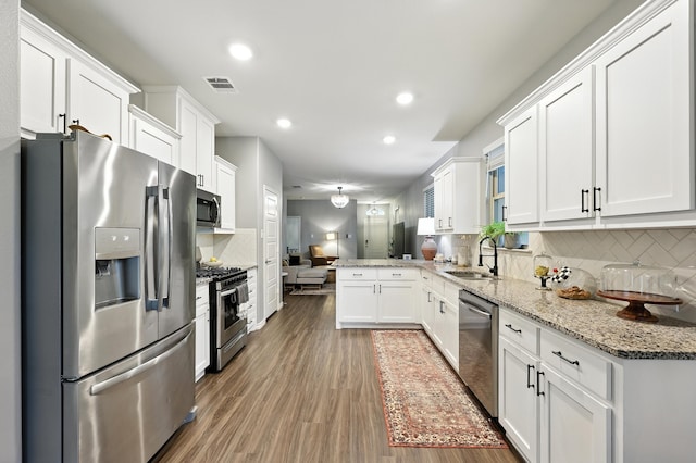 2136 Miramar Dr, Little Elm, TX 75068 - kitchen with appliances with stainless steel finishes, recessed lighting, white cabinets, tasteful backsplash, and a peninsula