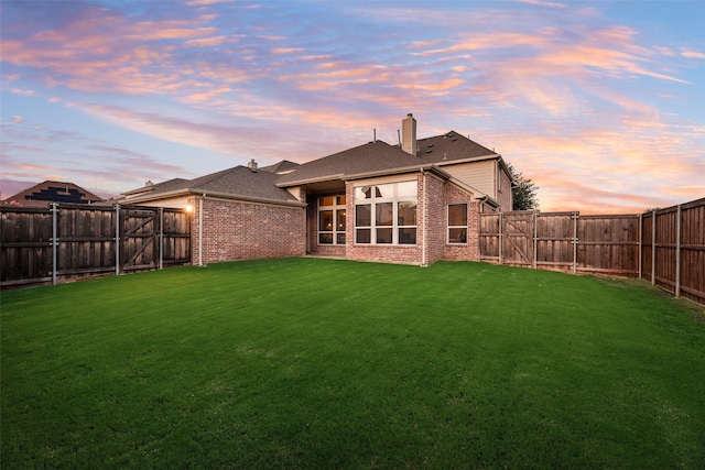 12517 Peace River Dr, Frisco, TX 75035 - back of property at dusk with brick siding, a fenced backyard, and a chimney