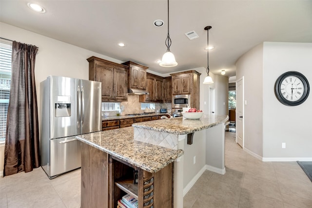 12517 Peace River Dr, Frisco, TX 75035 - kitchen featuring appliances with stainless steel finishes, under cabinet range hood, open shelves, light stone counters, and plenty of natural light