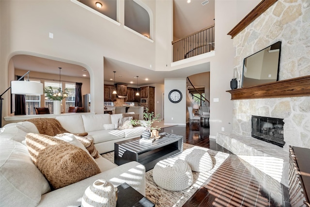 12517 Peace River Dr, Frisco, TX 75035 - living area with stairway, wood finished floors, a fireplace, a high ceiling, and arched walkways