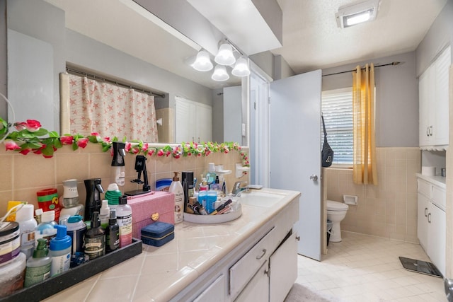 2008 Morningside Dr, Garland, TX 75041 - full bath featuring tile walls, vanity, tile patterned flooring, and a wainscoted wall