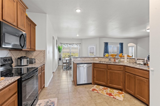 104 Knoll Ln, Decatur, TX 76234 - kitchen featuring black appliances, arched walkways, decorative backsplash, brown cabinets, and recessed lighting
