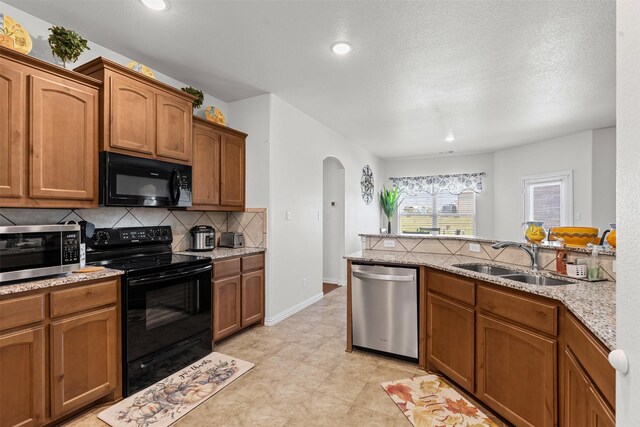 104 Knoll Ln, Decatur, TX 76234 - kitchen featuring black appliances, arched walkways, backsplash, brown cabinetry, and recessed lighting