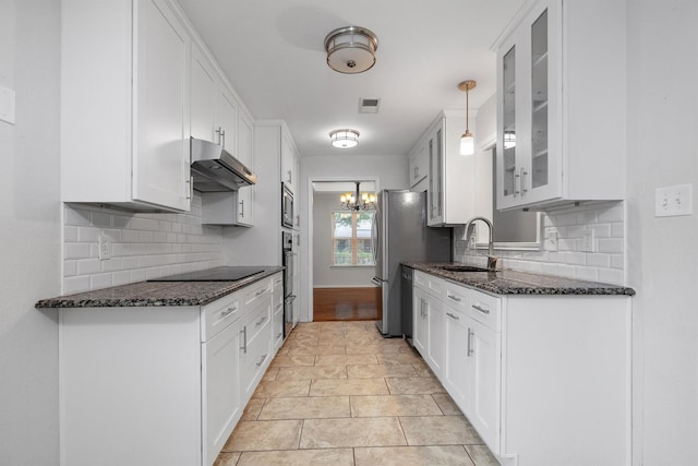 7422 Foxworth Dr, Dallas, TX 75248 - kitchen featuring under cabinet range hood, glass insert cabinets, backsplash, stainless steel appliances, and dark stone countertops