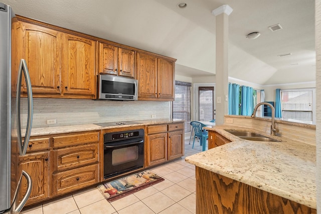 12313 Ark Rd, Frisco, TX 75035 - kitchen with black appliances, backsplash, brown cabinetry, light stone countertops, and lofted ceiling