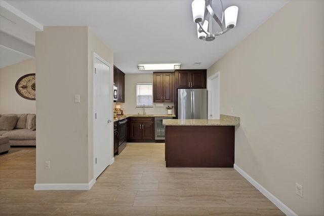 7104 Negril Ct, Fort Worth, TX 76137 - kitchen featuring appliances with stainless steel finishes, dark brown cabinetry, a peninsula, light stone counters, and hanging light fixtures