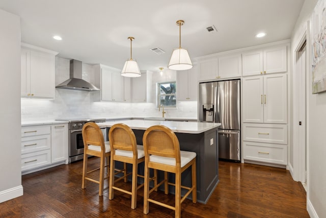 3505 Bentley Ct, Plano, TX 75093 - kitchen with wall chimney range hood, appliances with stainless steel finishes, a kitchen island, white cabinetry, and tasteful backsplash