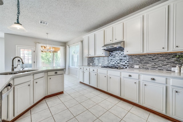 8224 Spring Valley Ln, Plano, TX 75025 - kitchen with under cabinet range hood, appliances with stainless steel finishes, light countertops, a chandelier, and plenty of natural light
