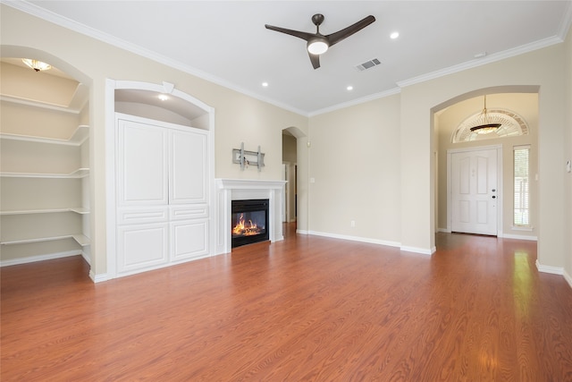 5853 Echo Bluff Dr, Haltom City, TX 76137 - unfurnished living room with ceiling fan, built in shelves, wood finished floors, arched walkways, and ornamental molding
