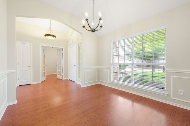 5853 Echo Bluff Dr, Haltom City, TX 76137 - empty room featuring a chandelier, plenty of natural light, arched walkways, lofted ceiling, and wood finished floors