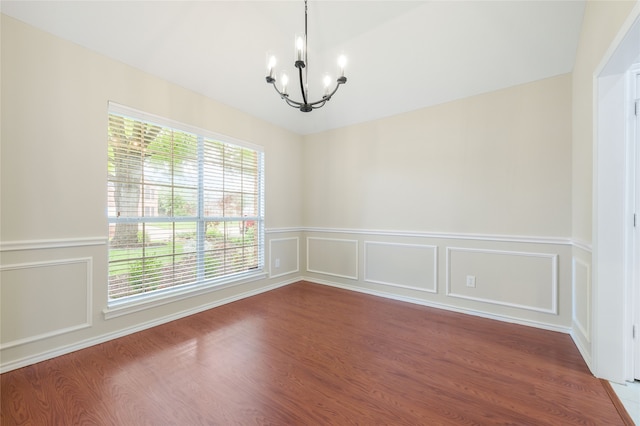 5853 Echo Bluff Dr, Haltom City, TX 76137 - spare room featuring a chandelier, wood finished floors, a wainscoted wall, and a decorative wall