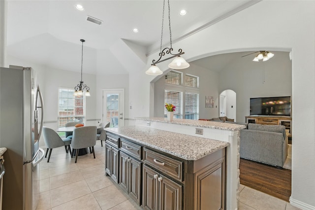 5413 Percy Priest St, Fort Worth, TX 76179 - kitchen with freestanding refrigerator, arched walkways, light tile patterned flooring, a center island, and vaulted ceiling