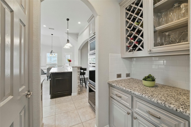 5413 Percy Priest St, Fort Worth, TX 76179 - kitchen with backsplash, arched walkways, light tile patterned flooring, pendant lighting, and light stone countertops