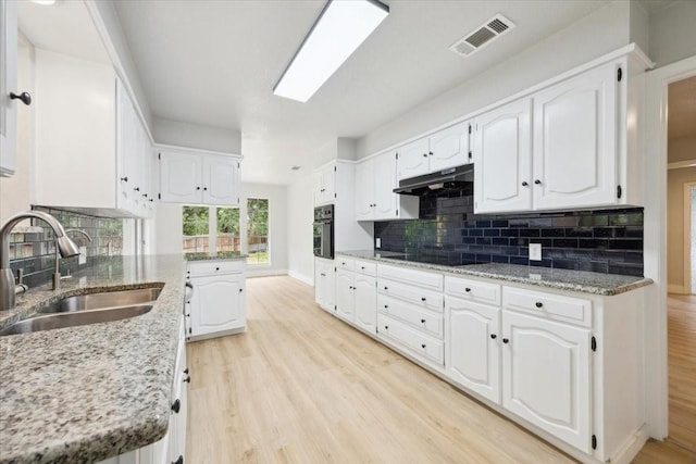 4132 Alava Dr, Fort Worth, TX 76133 - kitchen featuring under cabinet range hood, black appliances, light wood-type flooring, and white cabinets
