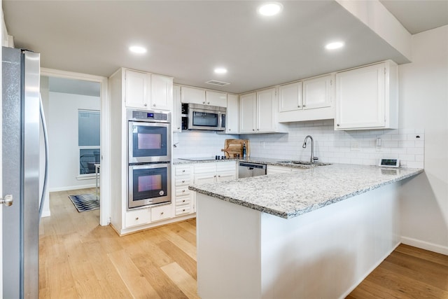 9707 Highland View Dr, Dallas, TX 75238 - kitchen featuring appliances with stainless steel finishes, light stone countertops, a peninsula, tasteful backsplash, and recessed lighting
