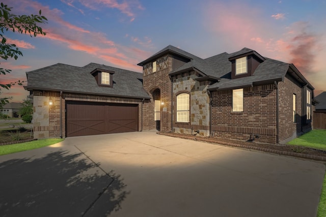 1256 Teton Dr, Burleson, TX 76028 - french country home with brick siding, driveway, a garage, and roof with shingles