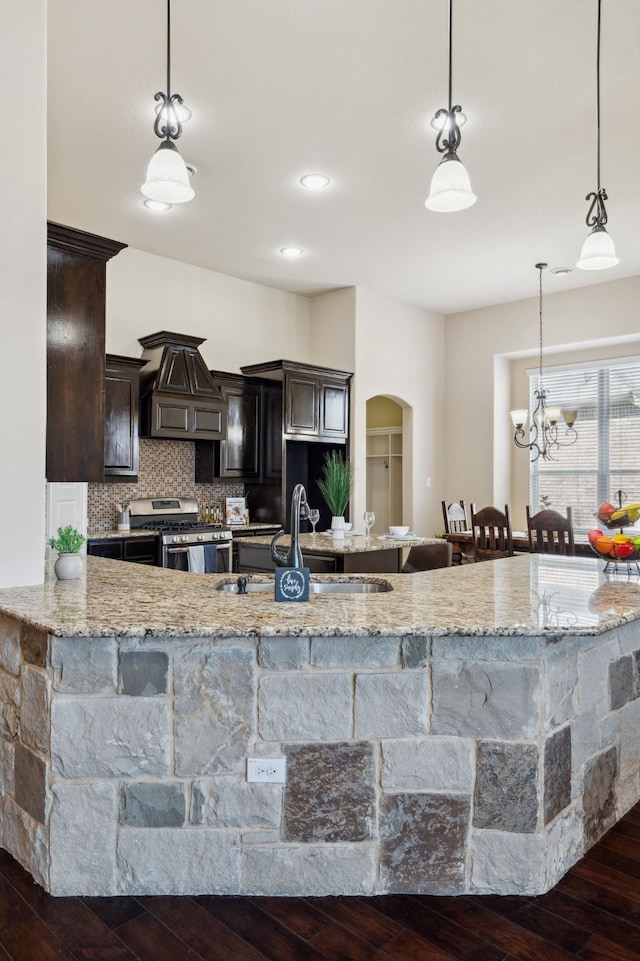 1256 Teton Dr, Burleson, TX 76028 - kitchen featuring stainless steel gas range, arched walkways, custom range hood, dark wood-style flooring, and dark brown cabinets
