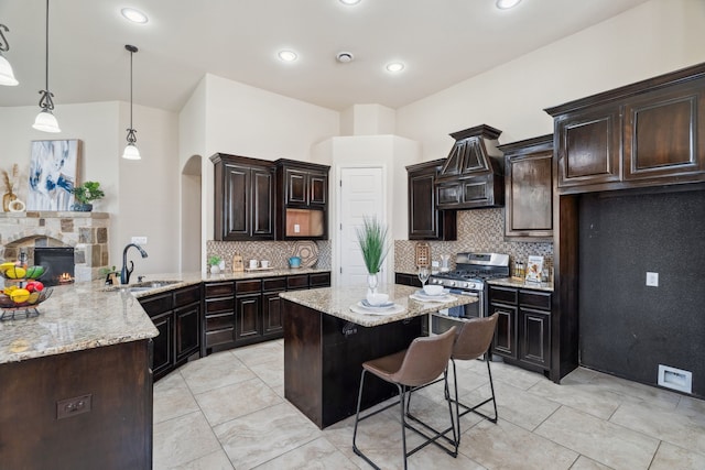 1256 Teton Dr, Burleson, TX 76028 - kitchen featuring gas range, arched walkways, light stone countertops, decorative backsplash, and a breakfast bar area