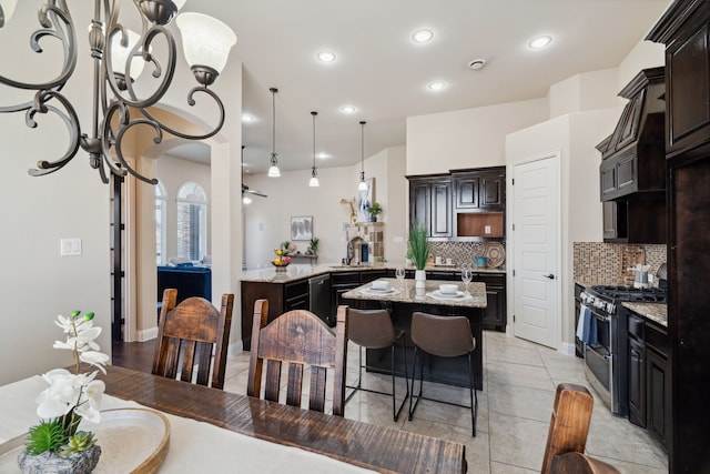 1256 Teton Dr, Burleson, TX 76028 - kitchen featuring range with two ovens, tasteful backsplash, a peninsula, light stone countertops, and a center island