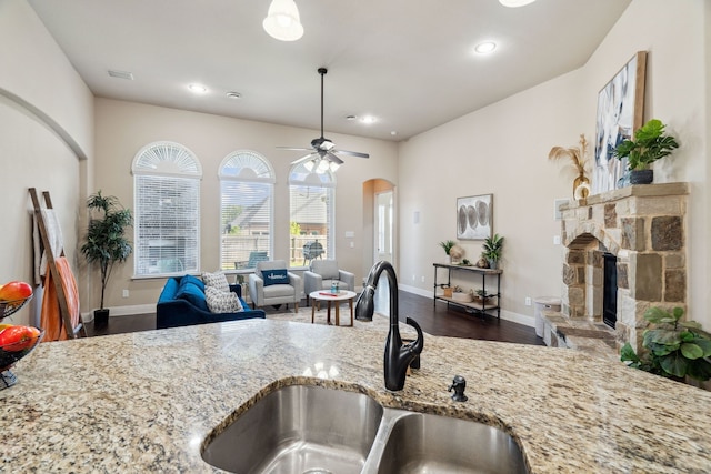 1256 Teton Dr, Burleson, TX 76028 - kitchen with light stone countertops, a ceiling fan, dark wood-style flooring, arched walkways, and recessed lighting