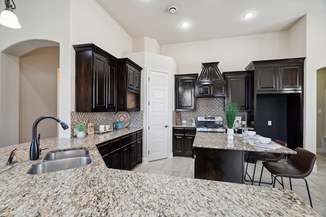 1256 Teton Dr, Burleson, TX 76028 - kitchen with stainless steel range with gas stovetop, arched walkways, backsplash, light stone counters, and recessed lighting