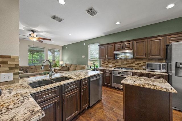 1045 Hillcrest Cir, Rockwall, TX 75087 - kitchen with appliances with stainless steel finishes, open floor plan, light stone counters, under cabinet range hood, and ceiling fan