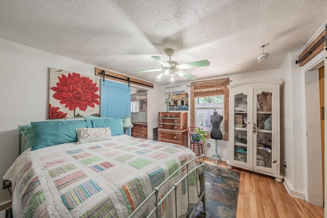 2057 Breezywood Dr, Flower Mound, TX 75022 - bedroom with a barn door, wood finished floors, a wall mounted air conditioner, and ceiling fan