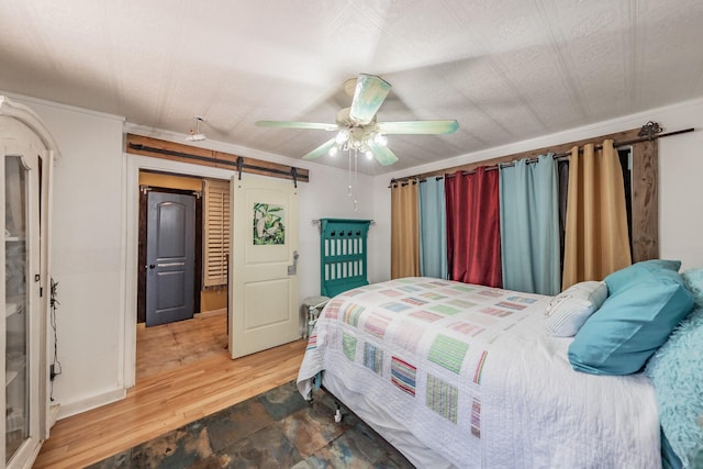 2057 Breezywood Dr, Flower Mound, TX 75022 - bedroom with a barn door, a ceiling fan, and wood finished floors