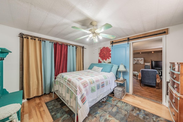 2057 Breezywood Dr, Flower Mound, TX 75022 - bedroom with a barn door, wood finished floors, and a ceiling fan